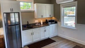Cocina con gabinetes blancos, un refrigerador de acero inoxidable, un microondas y un equipo de aire acondicionado.