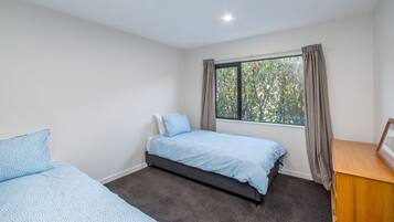 Ein Schlafzimmer mit einem Einzelbett, einem Schreibtisch und einem fenster mit Vorhängen.