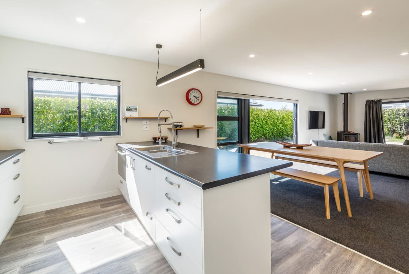 A modern kitchen with a central island, a dining area with a bench, and a sofa.