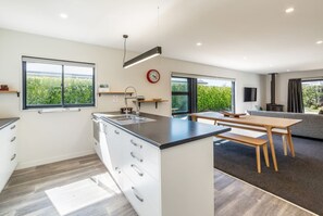 A modern kitchen with a central island, a dining area with a bench, and a sofa.