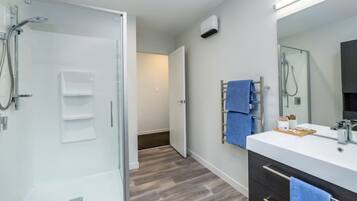 Ein modernes Badezimmer mit einer Duschkabine aus Glas, einem Waschtisch mit Spiegel und einem Handtuchhalter.