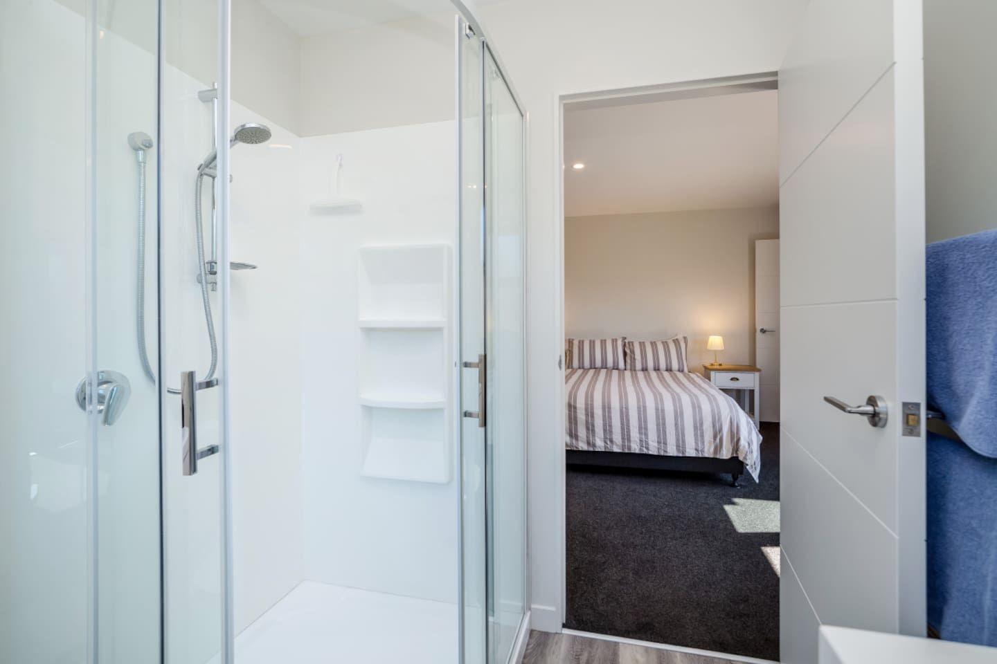 Ein modernes Badezimmer mit einer Duschkabine aus Glas, einer sichtbaren Dusche und einem Handtuchhalter.