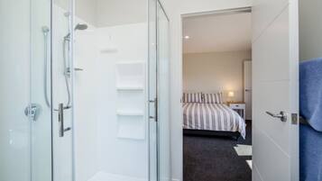 Ein modernes Badezimmer mit einer Duschkabine aus Glas, einer sichtbaren Dusche und einem Handtuchhalter.