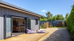 A modern house with a wooden deck, a dining area, and a small garden. - Private Escape – Seasonal Communal Pool, Tennis & Relaxed Living in Pinot Grove (Martinborough)