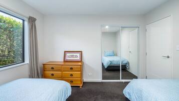 A bedroom with two beds, a dresser, a framed picture, and a sliding door leading to another room.