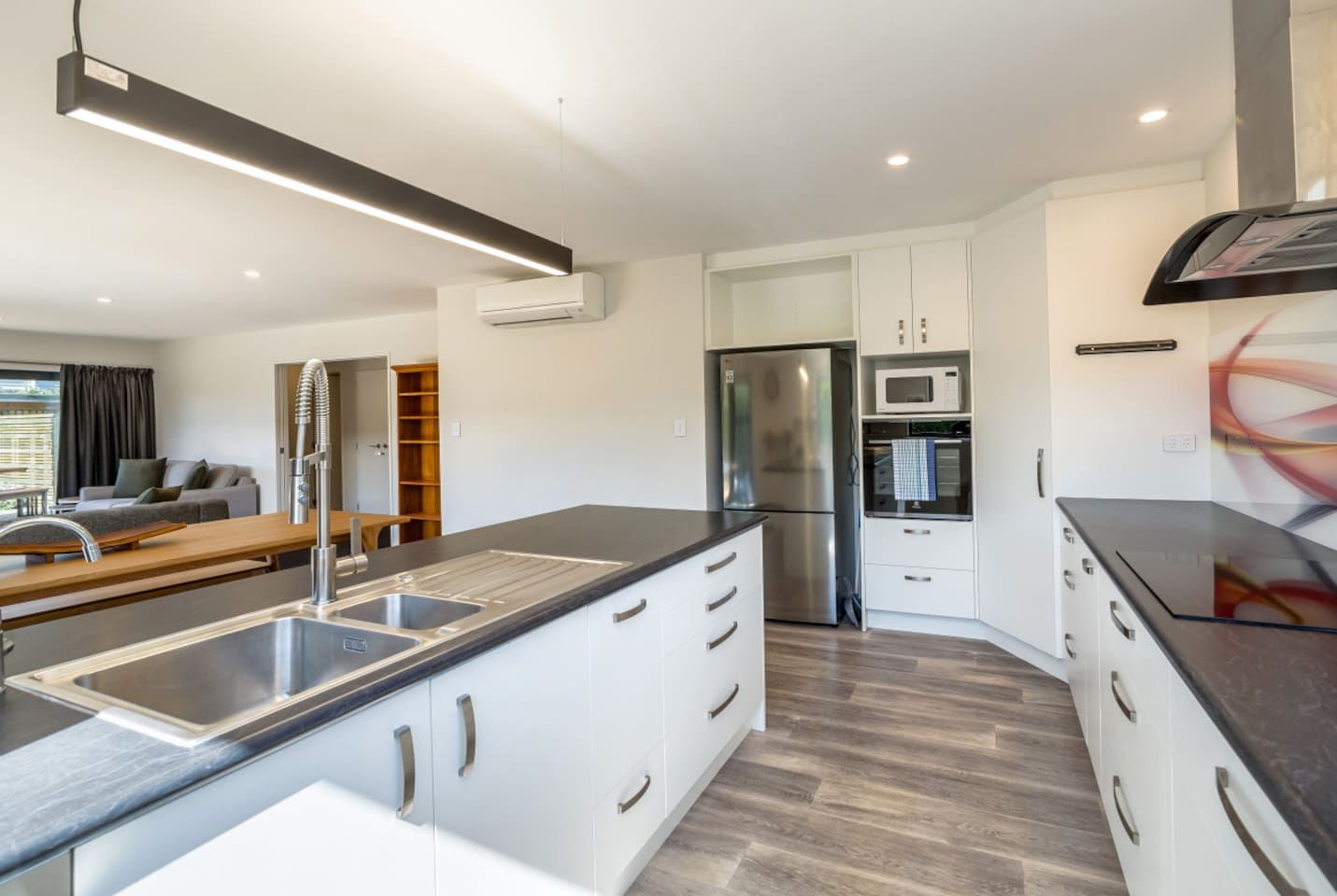 A modern kitchen with a central island, stainless steel appliances, and white cabinetry.