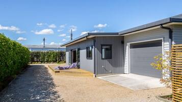 A modern two-story building with a gravel driveway, a covered patio, and a garage.