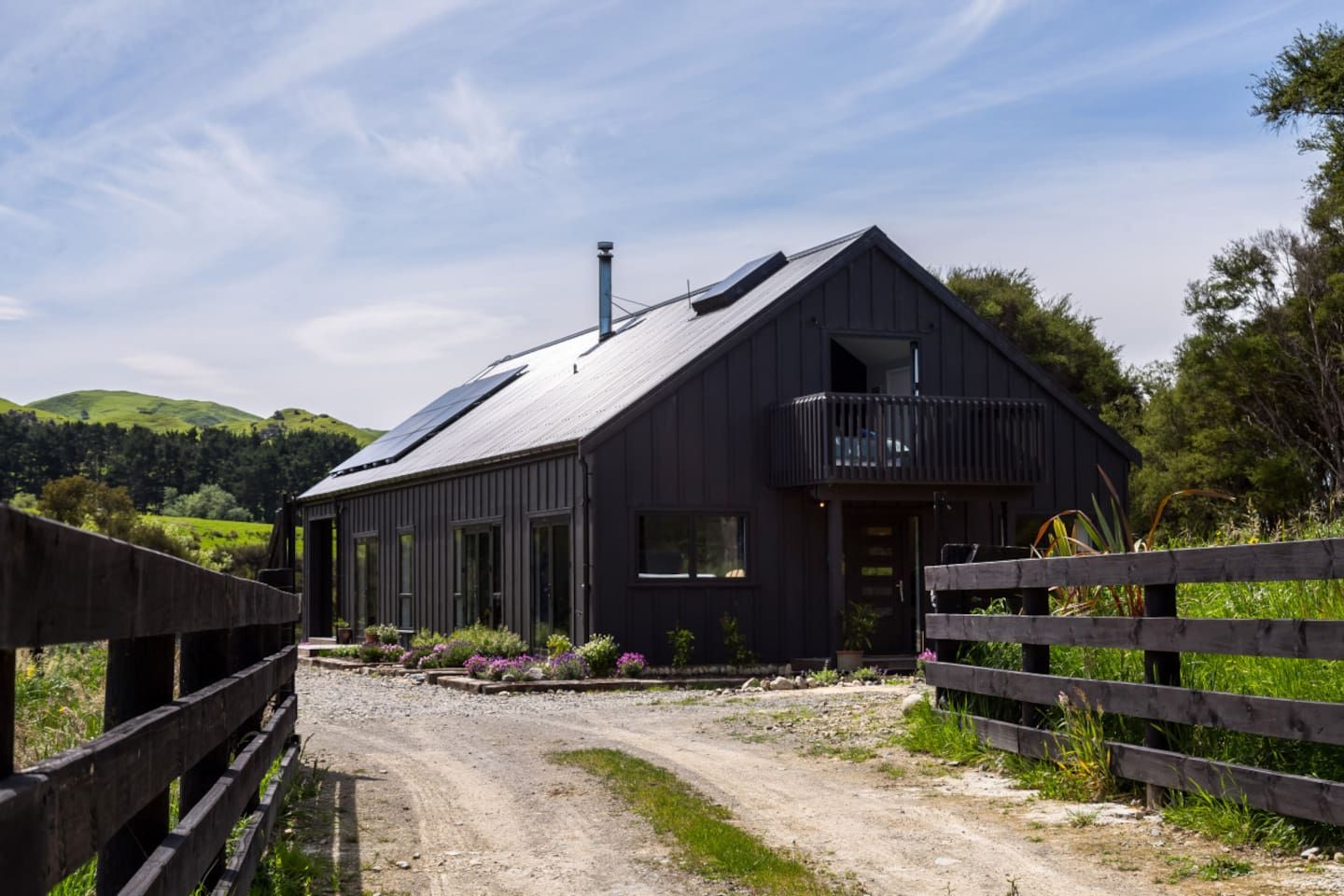 A modern farmhouse with a sloped roof, large windows, and a balcony.