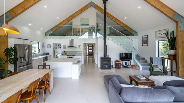 A spacious loft with a kitchen, dining area, living room, and a staircase leading to an upper level.