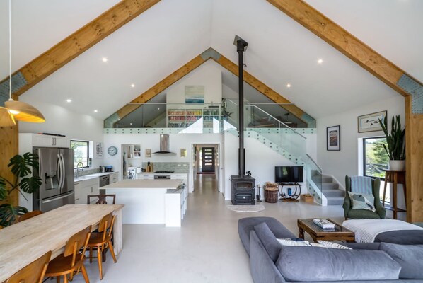 A spacious loft with a kitchen, dining area, living room, and a staircase leading to an upper level.