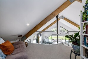 A loft-style room with a sloped ceiling, a built-in bookshelf, and a view of the outdoors.