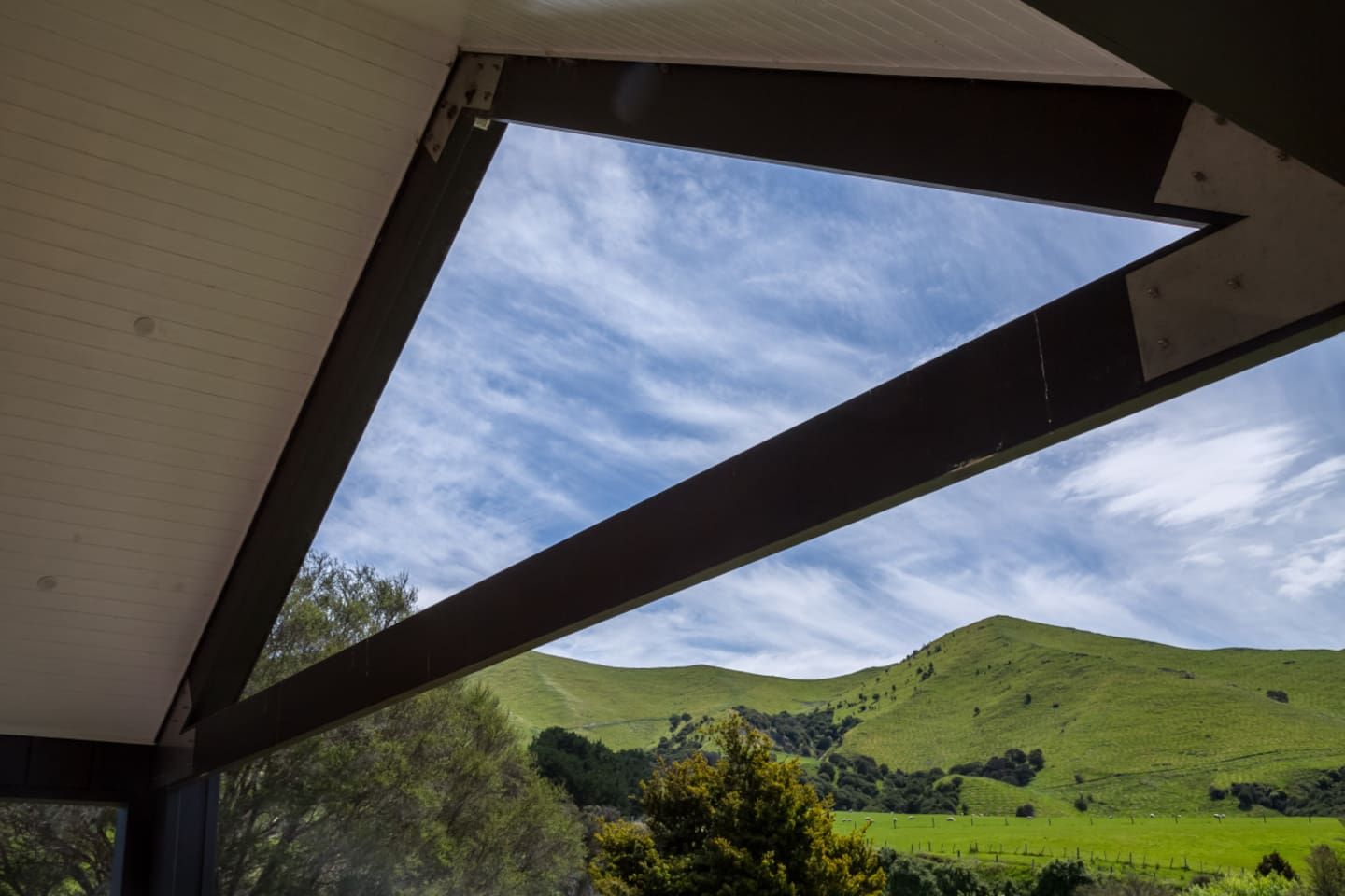 A room with a skylight, a view of green hills, and a clear sky.