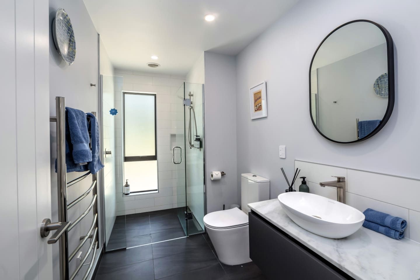 A modern bathroom with a glass shower enclosure, a white sink, and a toilet.