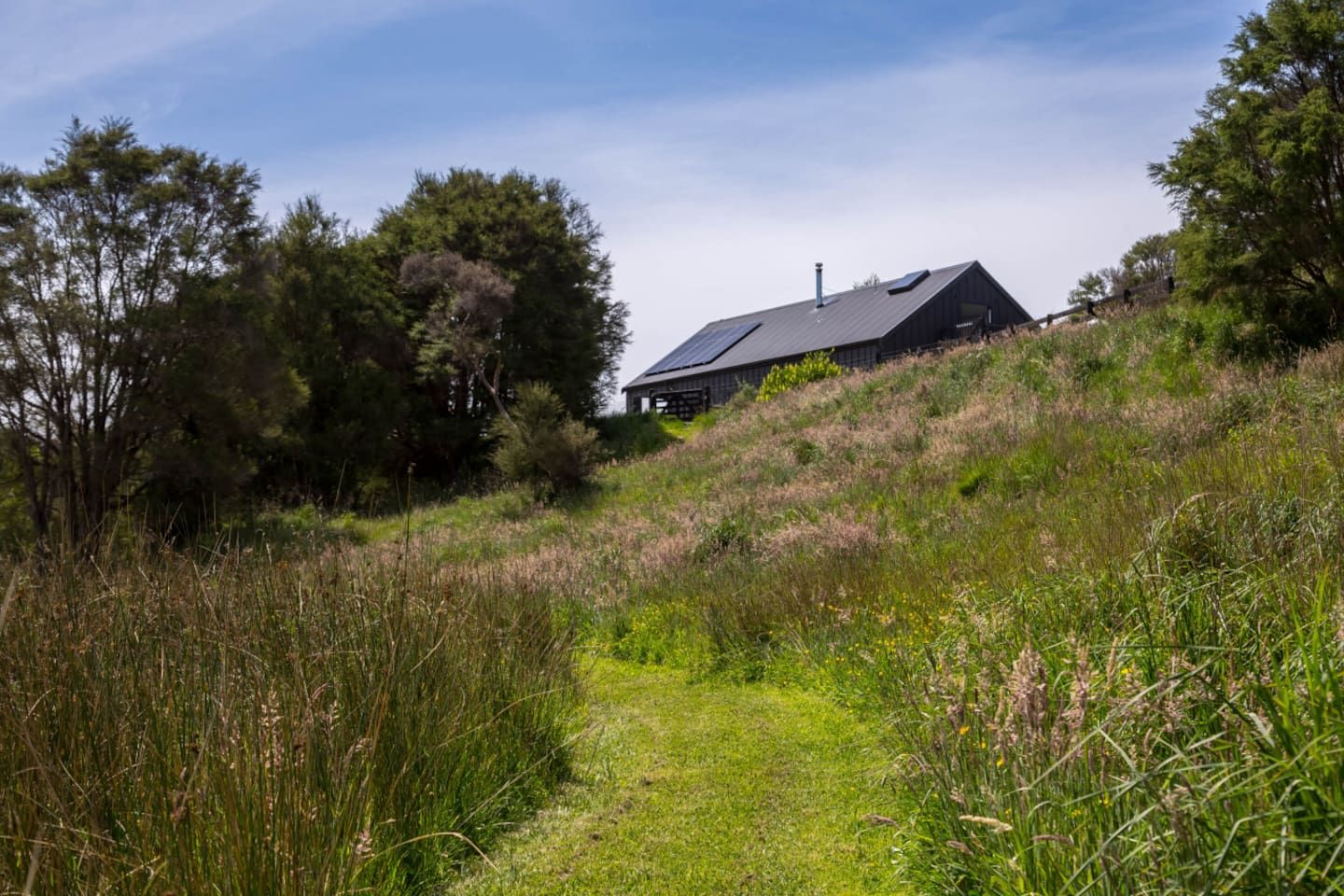 Ett hus på en grönskande kulle med en klar himmel.