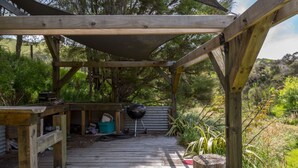 A wooden deck with a covered area, a barbecue grill, and outdoor storage.