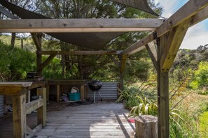 A wooden deck with a covered area, a barbecue grill, and outdoor storage.
