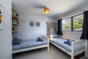 A room with two single beds, a bookshelf, a tapestry, and a window with curtains. - Farmhouse Retreat, Longbush (Hinakura)