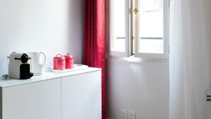 A room with a white cabinet, a window with red curtains, and a white door.