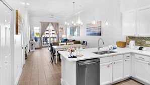Una cocina moderna con armarios blancos, una isla central con lavamanos e iluminación colgante.