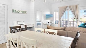 Una sala moderna con comedor, un conjunto de sofás, un televisor y un letrero en la pared que dice 'Beach House'.