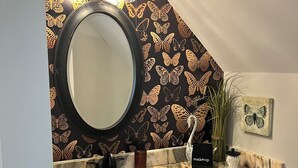 A bathroom with a round mirror, a sink, and a vanity with drawers. - The Butterfly Suite exudes an air of timeless elegance and natural splendor. Named in homage to the myriad species of butterflies that adorn the surrounding landscape. (Jasper)