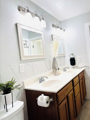 Un baño moderno con un tocador amplio, un espejo y un lavamanos.
