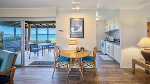 A modern kitchen with white cabinets and a dining area with a wooden table and wicker chairs.