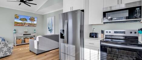 A modern kitchen with white cabinets, a stainless steel refrigerator, and a built-in oven.