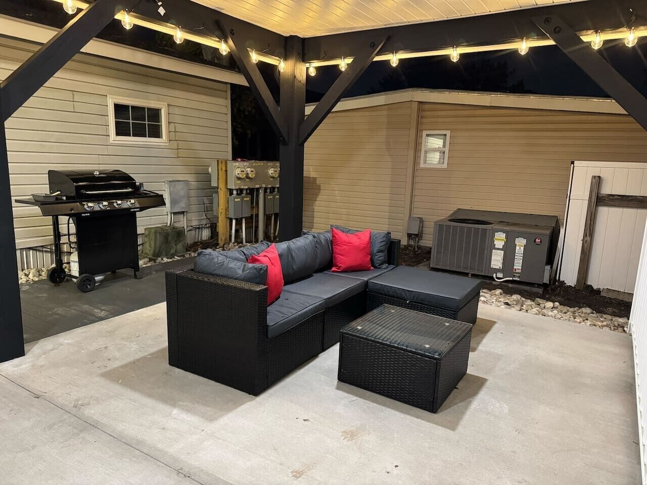 Un patio esterno con un divano componibile, un tavolino e un barbecue.