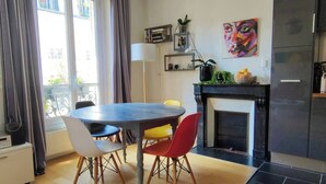 A modern kitchen with a dining table, chairs, a fireplace, and a refrigerator. - Cosy Parisian charm Paris 12e Montgallet  (Paris)