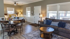 A living room with a sofa, a dining table with chairs, a ceiling fan, and a window with blinds. - Bungalow #5 by Polo House and Bungalows (Santa Ynez)