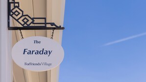 A sign hanging from a building's exterior, reading 'The Faraday For Friends Village.' - Bungalow #5 by Polo House and Bungalows (Santa Ynez)