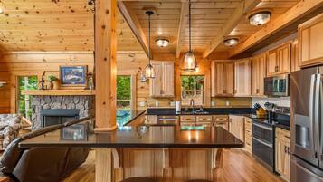 Una cocina moderna con armarios de madera, una isla central, electrodomésticos de acero inoxidable e iluminación colgante.