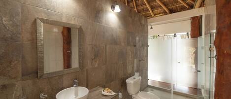 A modern bathroom with a large mirror, a bowl sink, a toilet, and a glass-enclosed shower area.