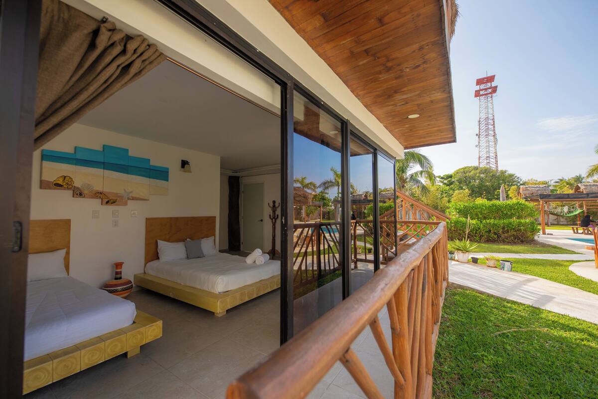 Habitación de hotel con dos camas, techo de madera y vistas a una piscina y zona exterior.