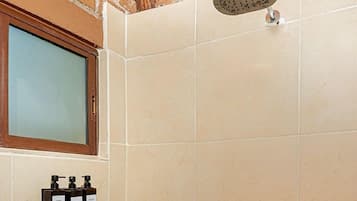 Ducha con cabezal de ducha de mano, una ventana y dispensador de jabón en la pared.