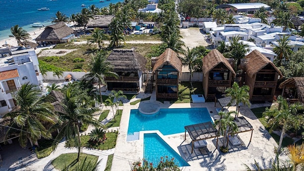 Ein Resort mit Pool, strohgedeckten Gebäuden und Palmen.