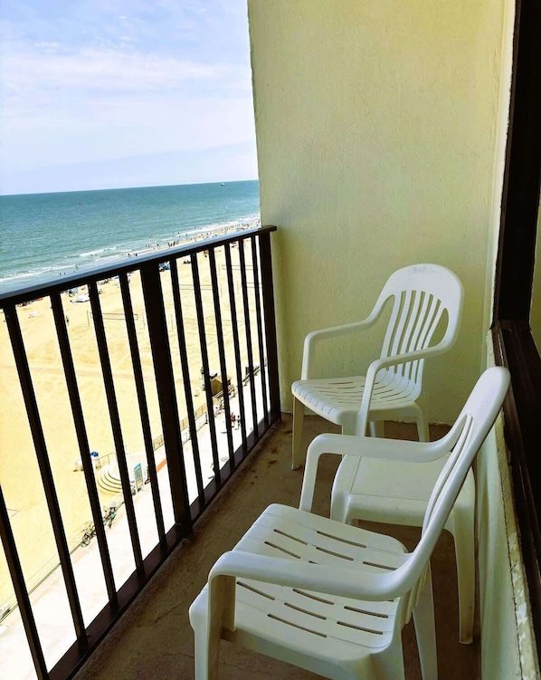 Enjoy the serene beach view from this balcony with two comfortable chairs.