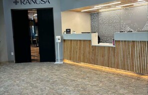 Welcome to RANSA, where guests can check in at the reception desk, featuring a digital screen and a unique vertical slat design.