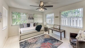 Una habitación amplia con cama, sofá, una mesita y ventilador de techo.