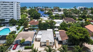 Zona residencial costera con un edificio grande, una piscina y casas de diferentes estilos de techo.