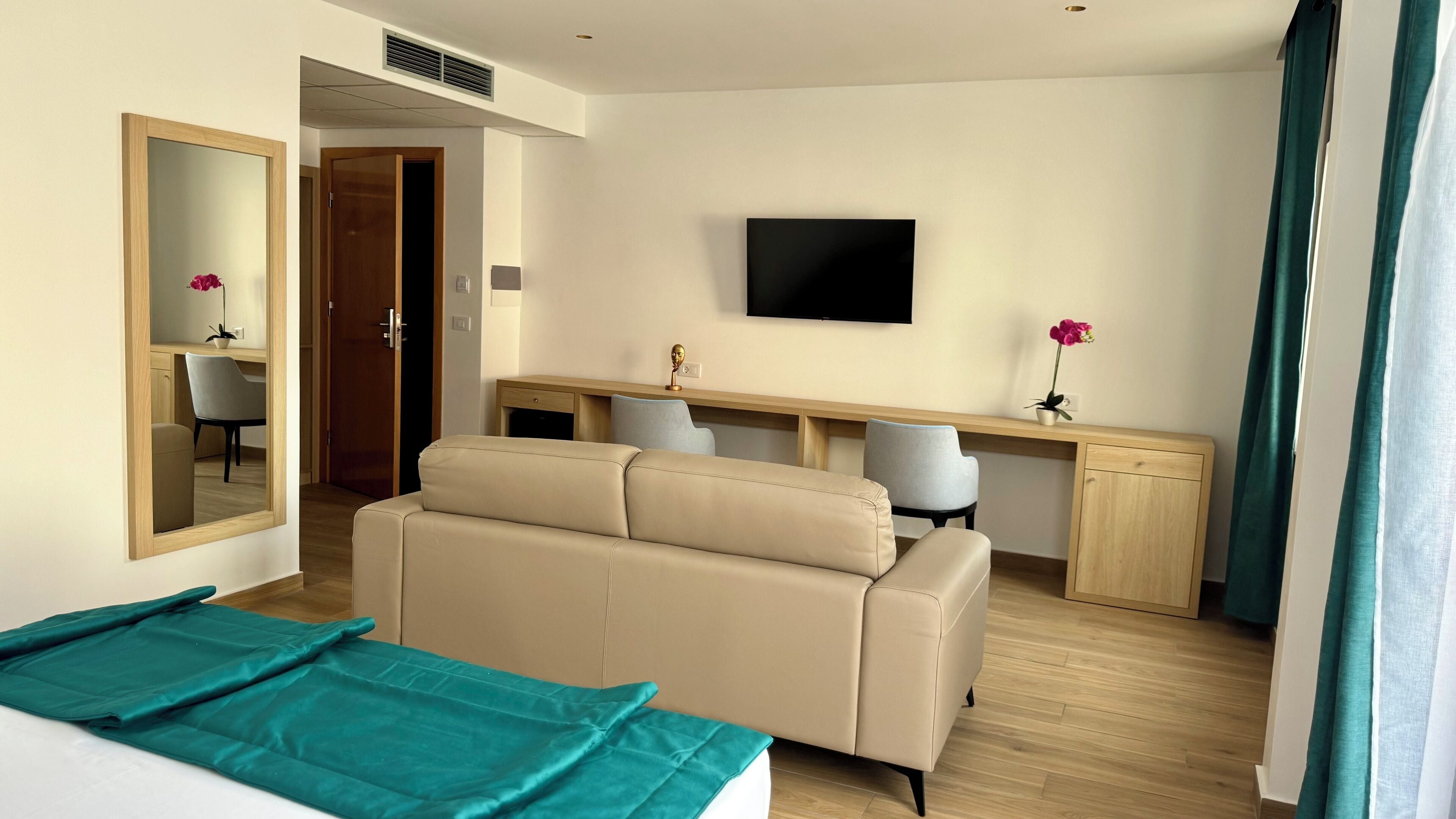 A hotel room with a bed, a desk, a TV, and a mirror.