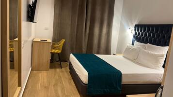 Une chambre d’hôtel moderne équipée d’un lit, d’un bureau, d’une chaise et d’un grand miroir.