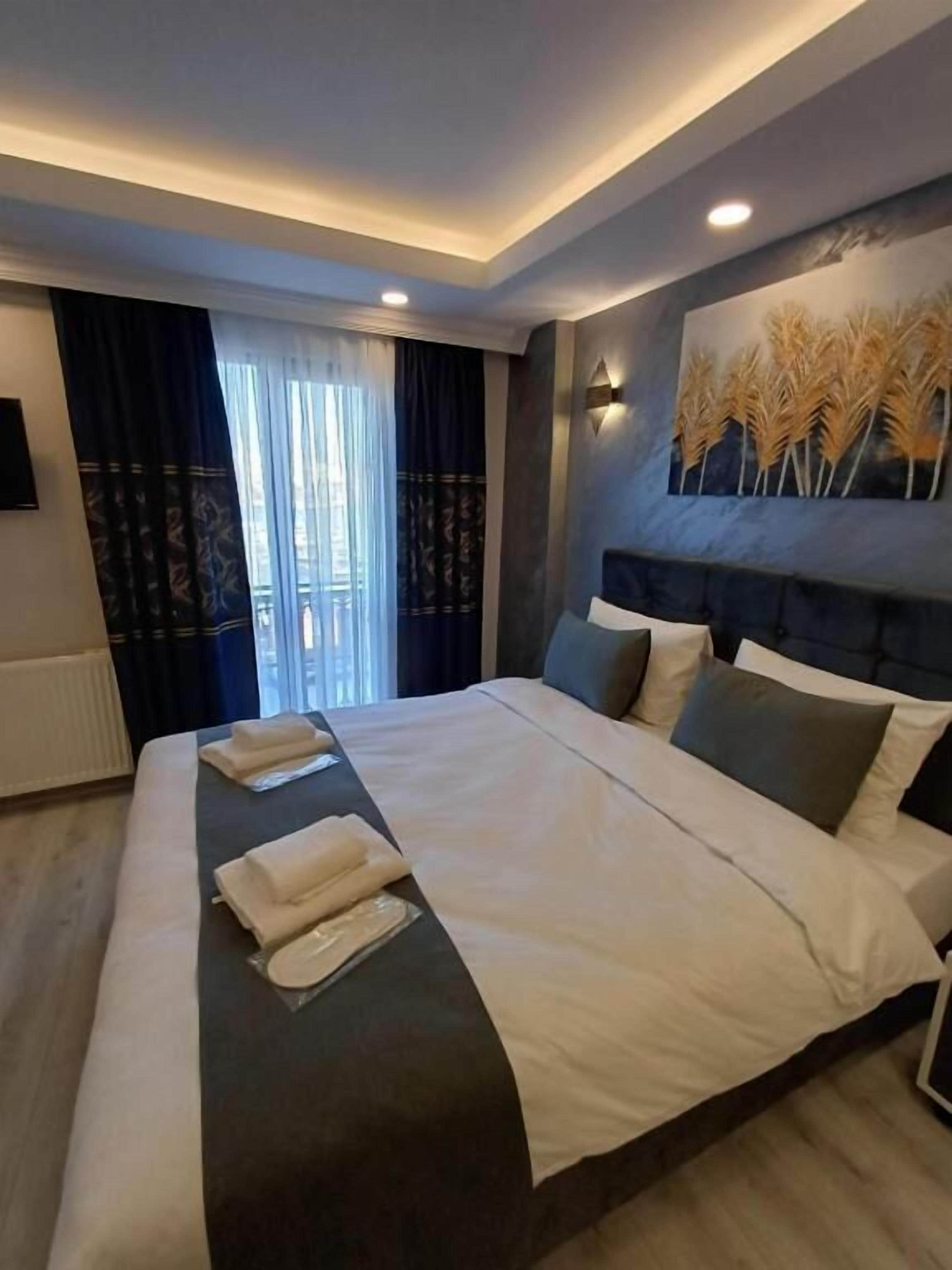 Een moderne hotelkamer met een groot bed, een hoofdbord met decoratief paneel, een wandtelevisie en een raam met gordijnen.