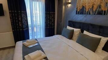 Een moderne hotelkamer met een groot bed, een hoofdbord met decoratief paneel, een wandtelevisie en een raam met gordijnen.