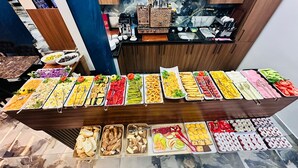 Un bufé con diversas opciones de comida, incluyendo ensaladas, frutas y pasteles.
