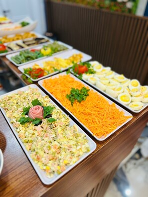 Een buffet met diverse gerechten, waaronder salades, gesneden groenten en gekookte eieren.