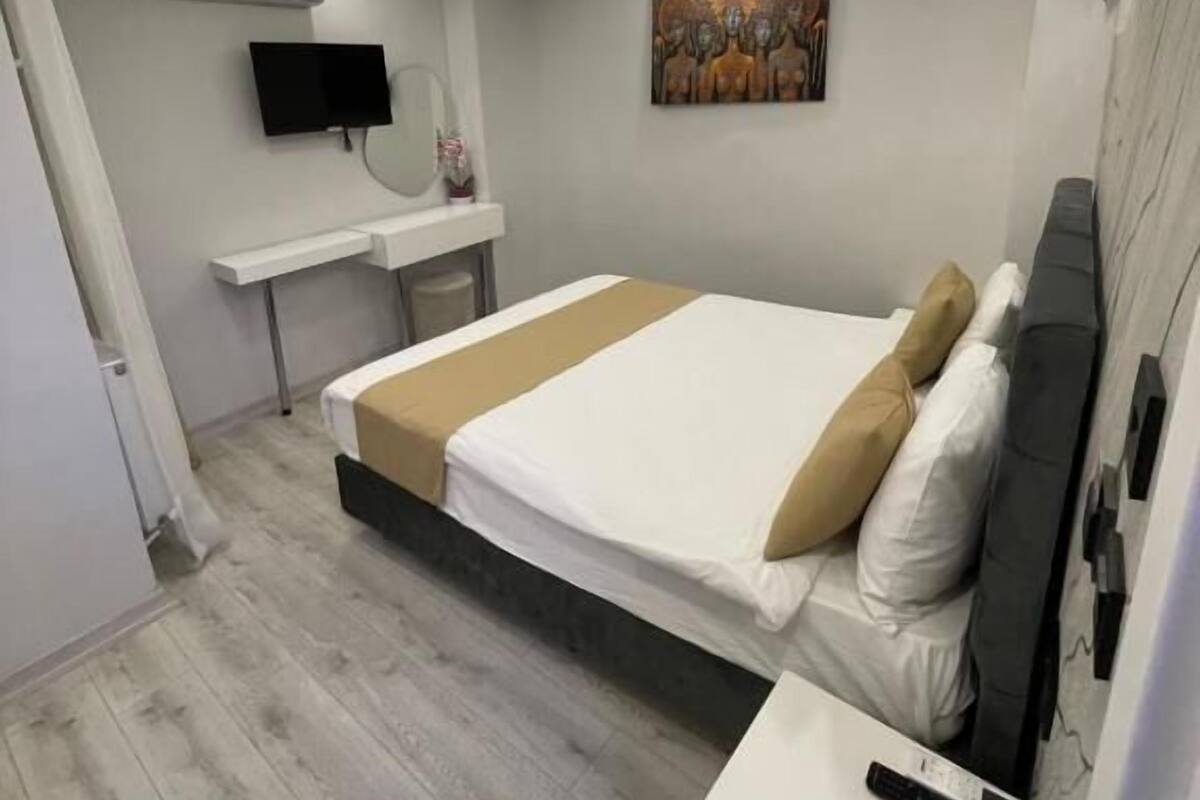 A modern bedroom with a bed, bedside table, and a mounted TV.