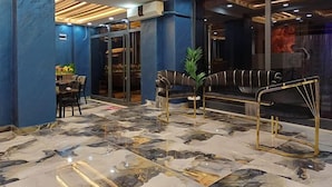 Un vestíbulo moderno con suelo de mármol, un sofá y una zona de comedor.