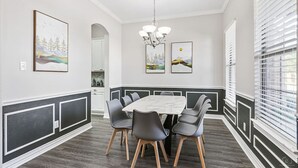 Ein Esszimmer mit einem Marmortisch, grauen Stühlen und einer Pendelleuchte.